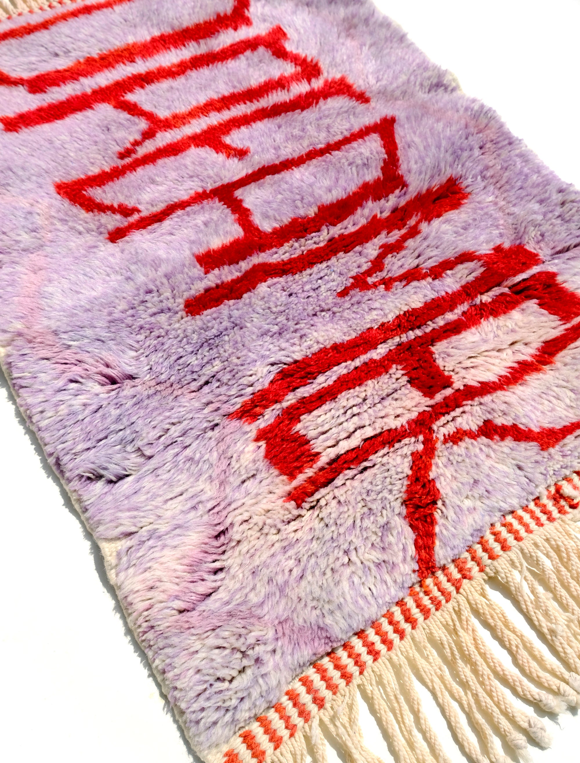 Experience the elegance of our 'Royal Dreamscape Rug,' featuring a handwritten 'Dreamer' in red yarn. The light purple base is intricately woven with a subtle Berber pattern, creating a truly unique and enchanting addition to your space. Elevate your decor with this regal blend of design and craftsmanship, where classic beauty meets artistic flair.