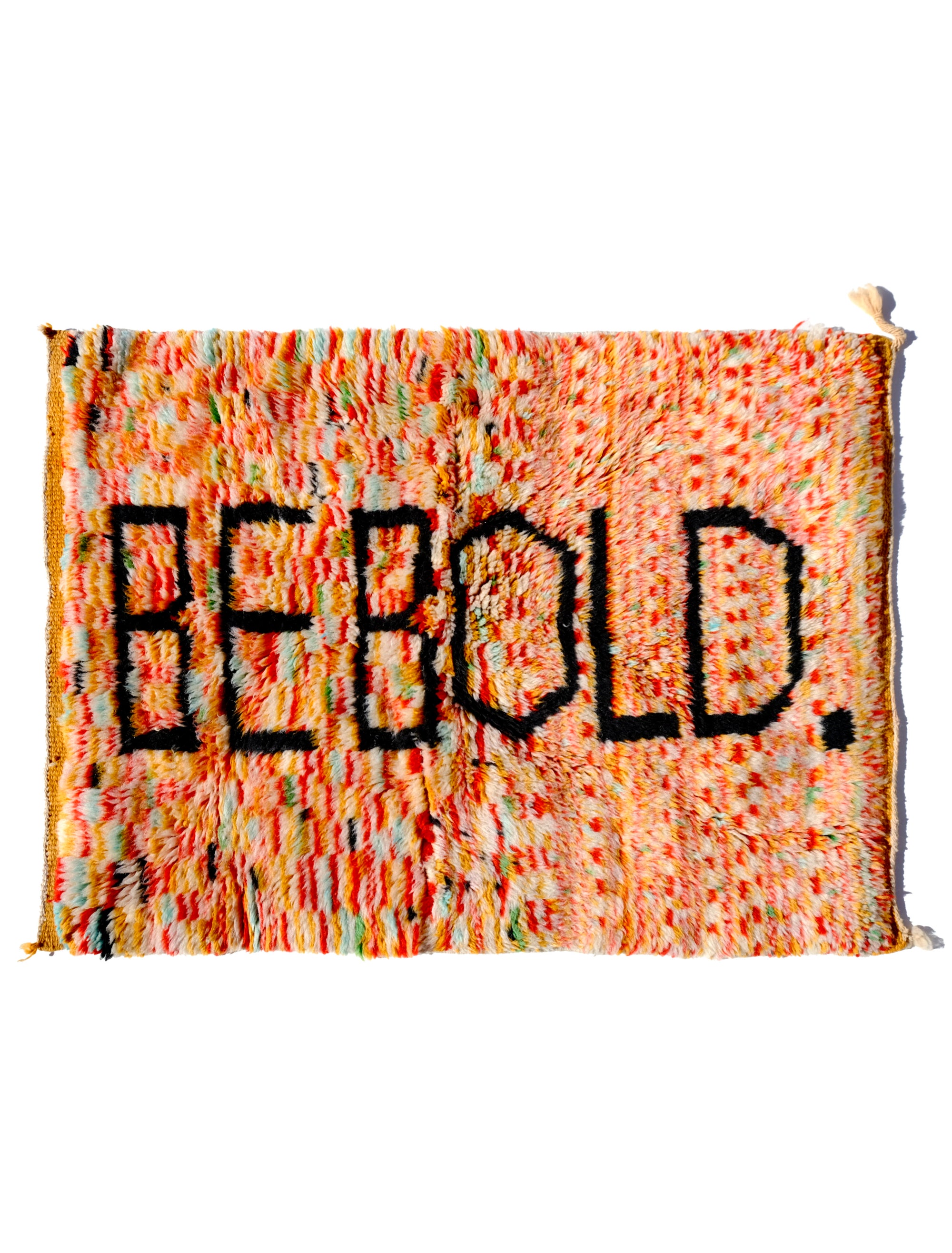 Elevate your space with the 'Tangerine Radiance Rug.' Handmade in the Atlas Mountains, this vibrant rug features a unique checkerboard pattern in warm tangerine tones. The focal point, proclaiming 'BE BOLD' in black letters, adds a touch of inspiration. With a fuzzy texture and meticulous craftsmanship, this rug brings warmth and positive energy to any room.  Size: 80 x 120cm / 31 x 47in 