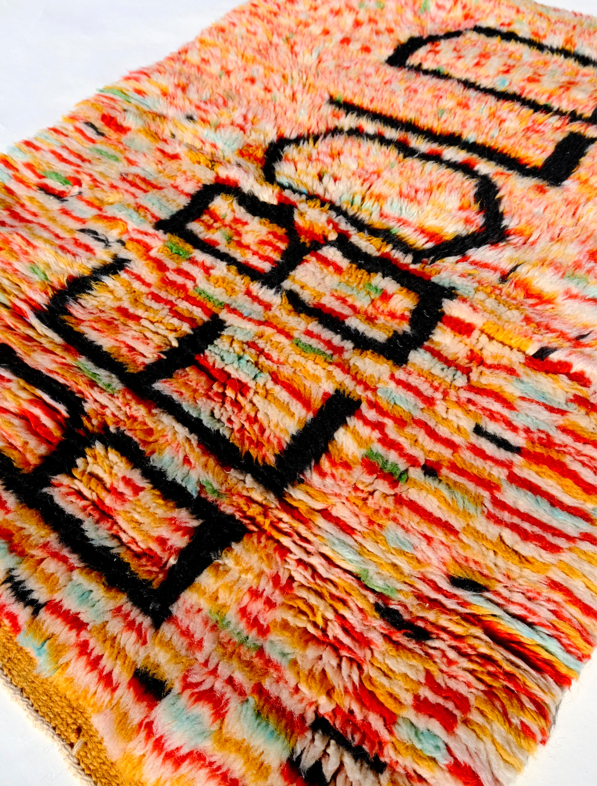 Elevate your space with the 'Tangerine Radiance Rug.' Handmade in the Atlas Mountains, this vibrant rug features a unique checkerboard pattern in warm tangerine tones. The focal point, proclaiming 'BE BOLD' in black letters, adds a touch of inspiration. With a fuzzy texture and meticulous craftsmanship, this rug brings warmth and positive energy to any room.  Size: 80 x 120cm / 31 x 47in 