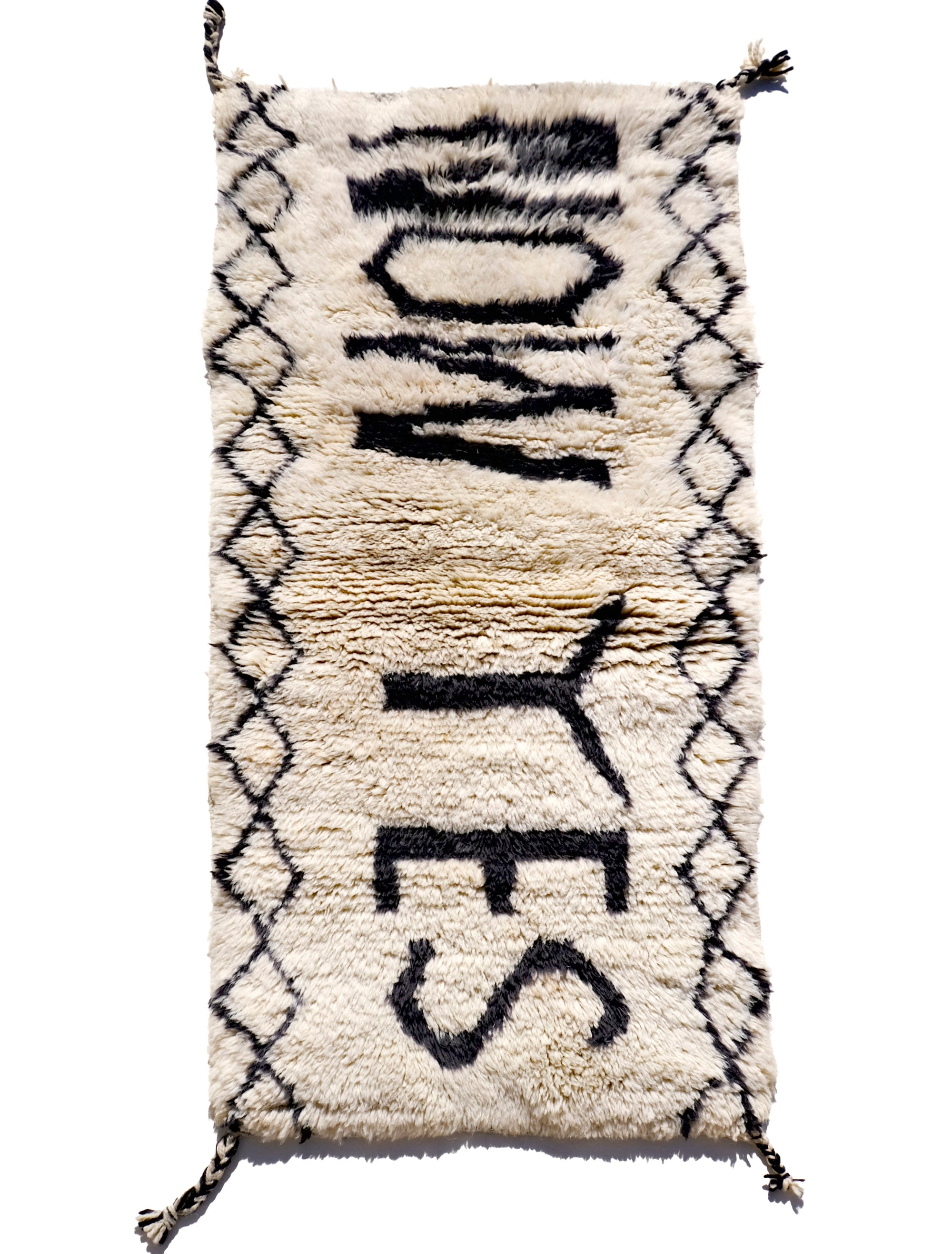 Infuse your space with positivity using the "Ivory In the Moment Rug." Handmade in the Atlas Mountains, its soft ivory base showcases the empowering phrase "NOW YES" at the center. Modern and Moroccan-inspired with small diamond patterns, this unique rug adds style and positivity to your home.