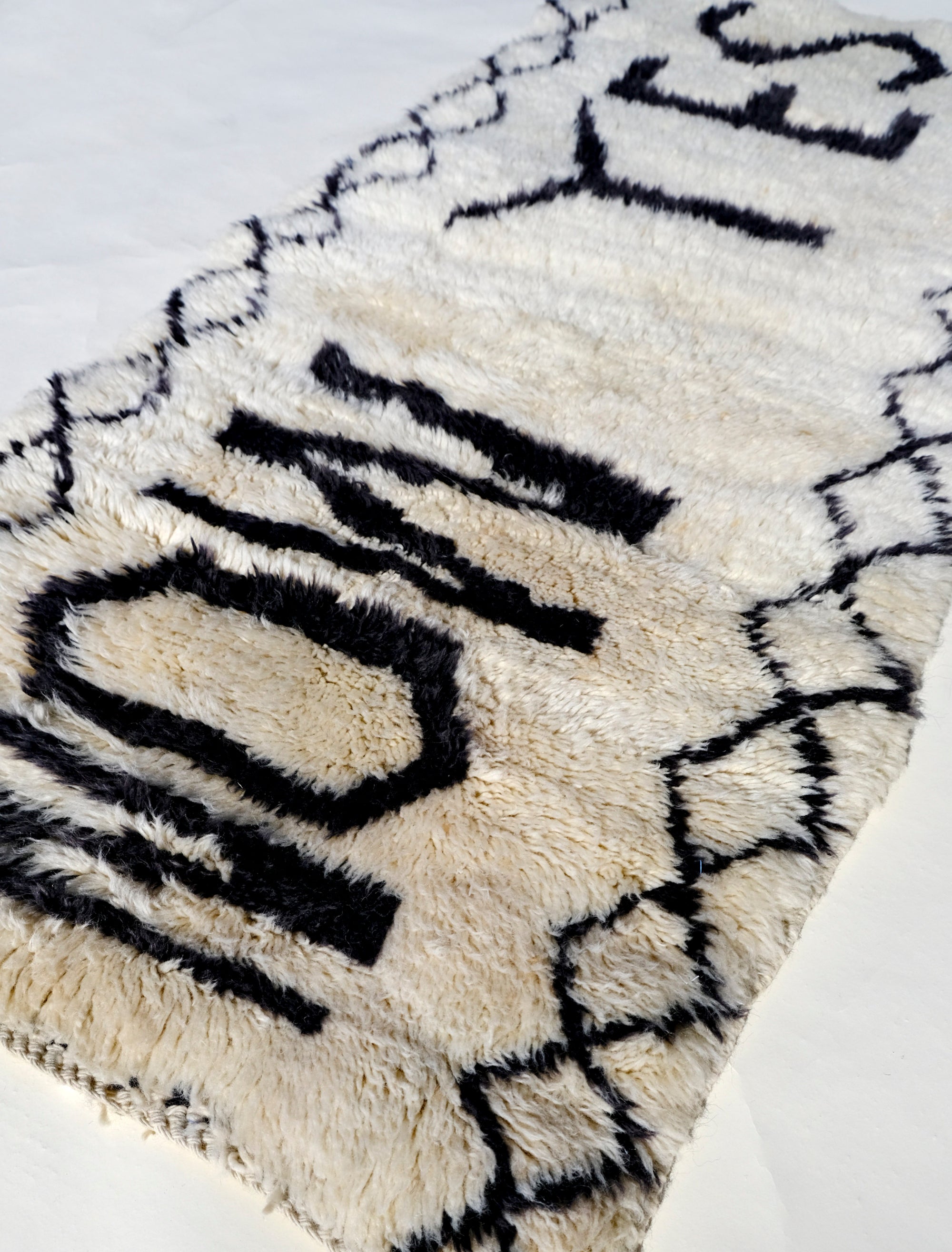 Infuse your space with positivity using the "Ivory In the Moment Rug." Handmade in the Atlas Mountains, its soft ivory base showcases the empowering phrase "NOW YES" at the center. Modern and Moroccan-inspired with small diamond patterns, this unique rug adds style and positivity to your home.