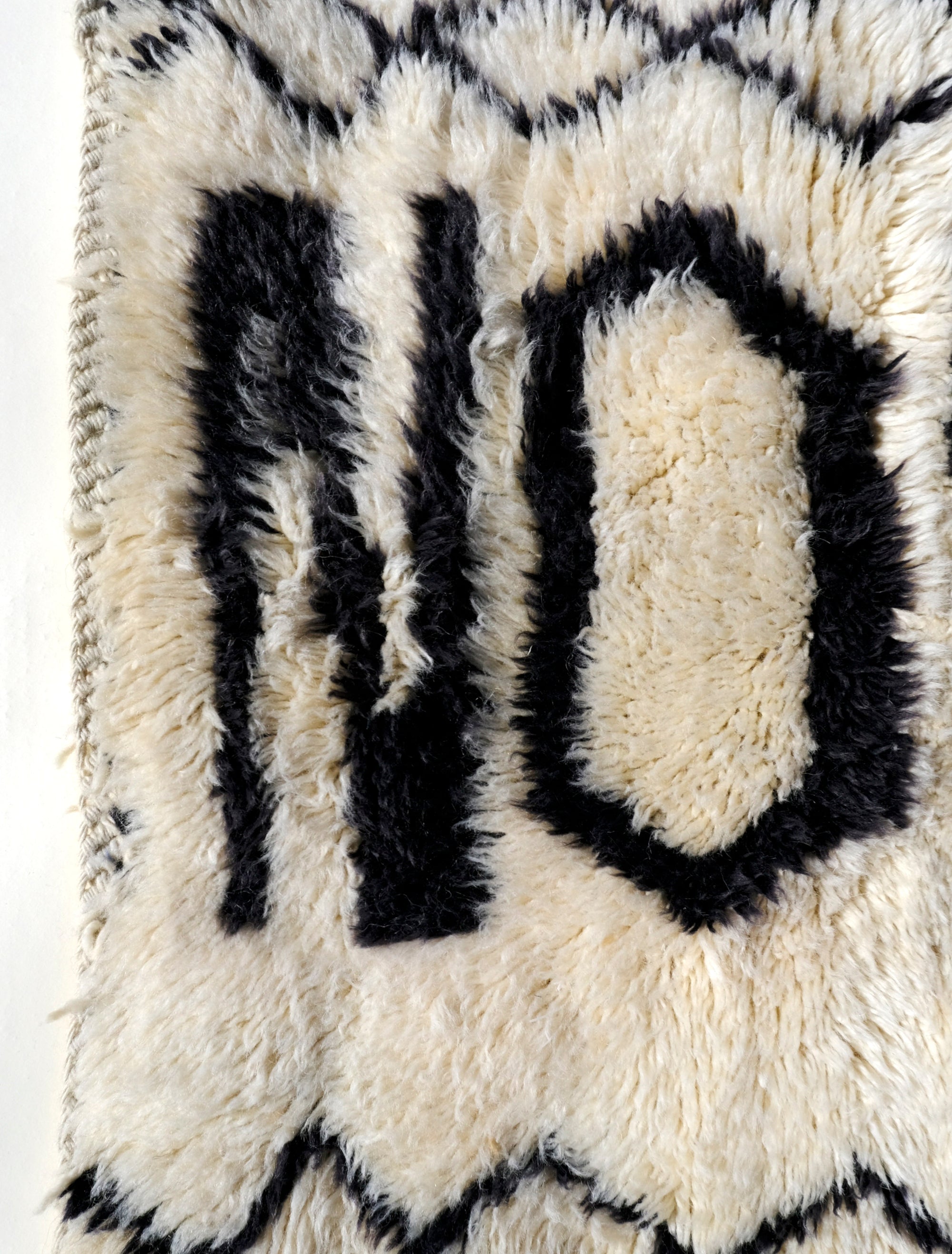 Infuse your space with positivity using the "Ivory In the Moment Rug." Handmade in the Atlas Mountains, its soft ivory base showcases the empowering phrase "NOW YES" at the center. Modern and Moroccan-inspired with small diamond patterns, this unique rug adds style and positivity to your home.