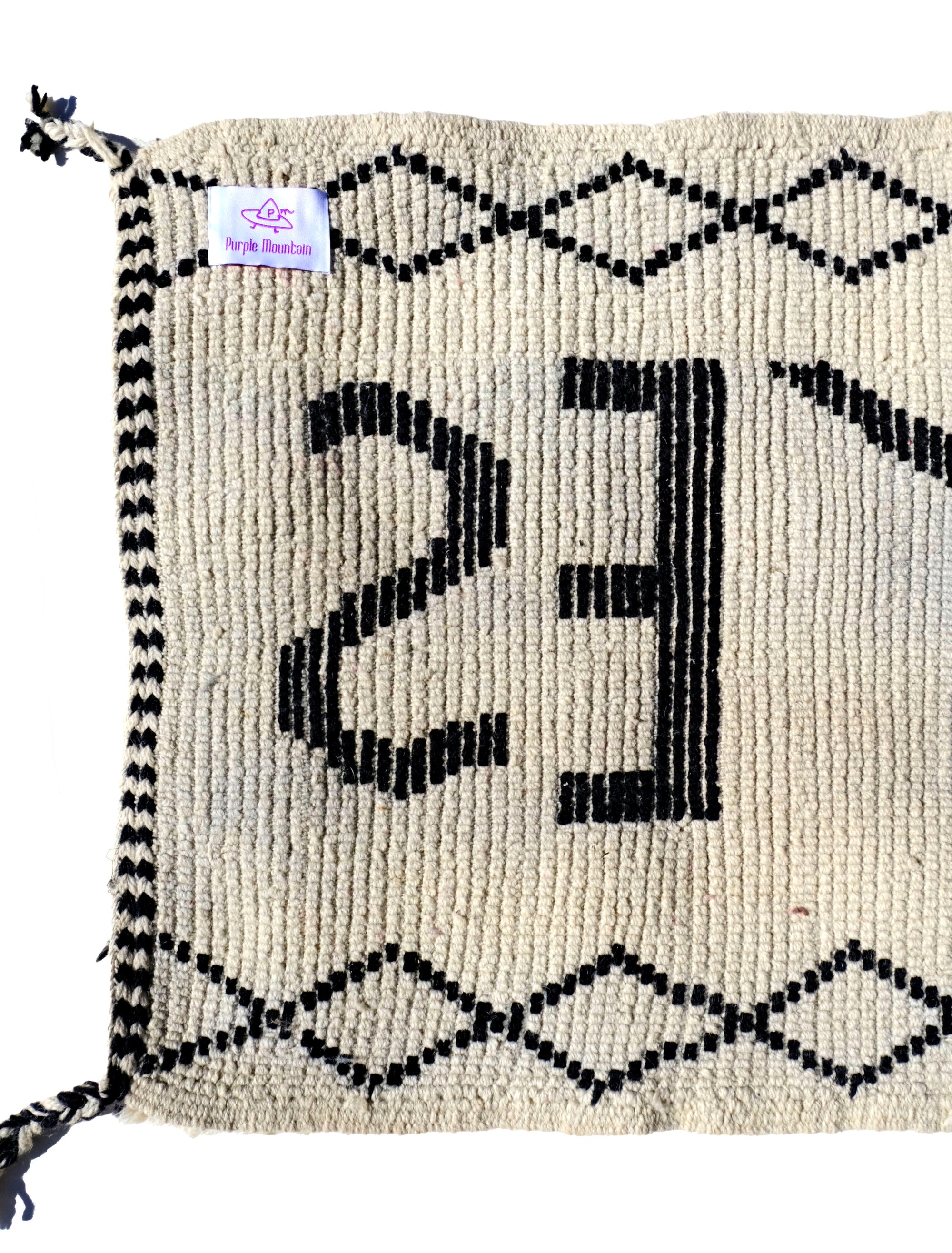 Infuse your space with positivity using the "Ivory In the Moment Rug." Handmade in the Atlas Mountains, its soft ivory base showcases the empowering phrase "NOW YES" at the center. Modern and Moroccan-inspired with small diamond patterns, this unique rug adds style and positivity to your home.