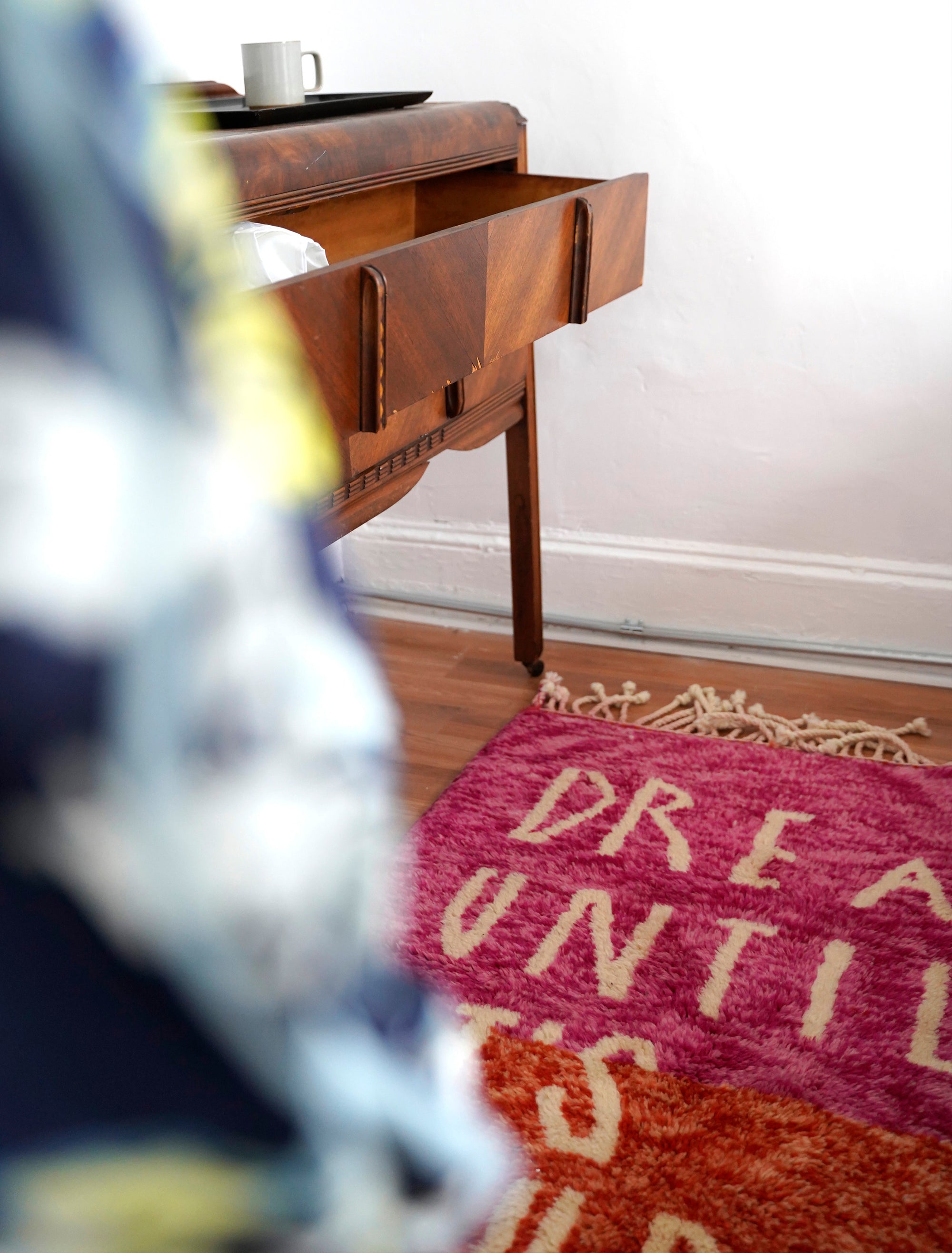 Introducing the enchanting 'Rosy Dreamscape Rug,' a delightful fusion of pink and red yarns forming a playful base, with the inspiring phrase 'Dream Until It Is Your Reality' expertly woven in white yarn. Elevate your space with this captivating blend of colors and motivational message, creating a joyful and imaginative ambiance that adds a touch of beauty and positivity to your home.