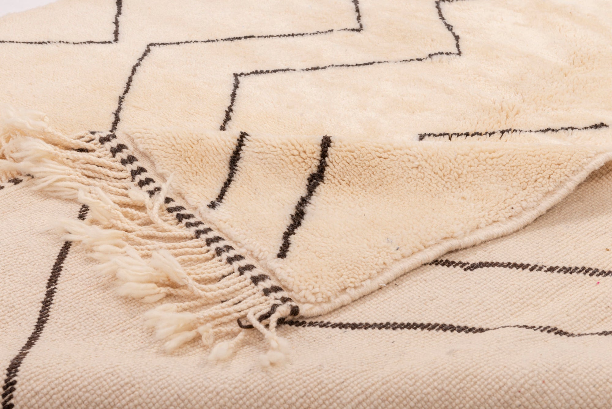 Elevate your home with our 'Ivory Zigzag Delight Rug.' Featuring a classic ivory base with understated black zigzag patterns and charming tassels, this rug effortlessly combines traditional charm with contemporary style, making it an ideal choice to complement your interior design
