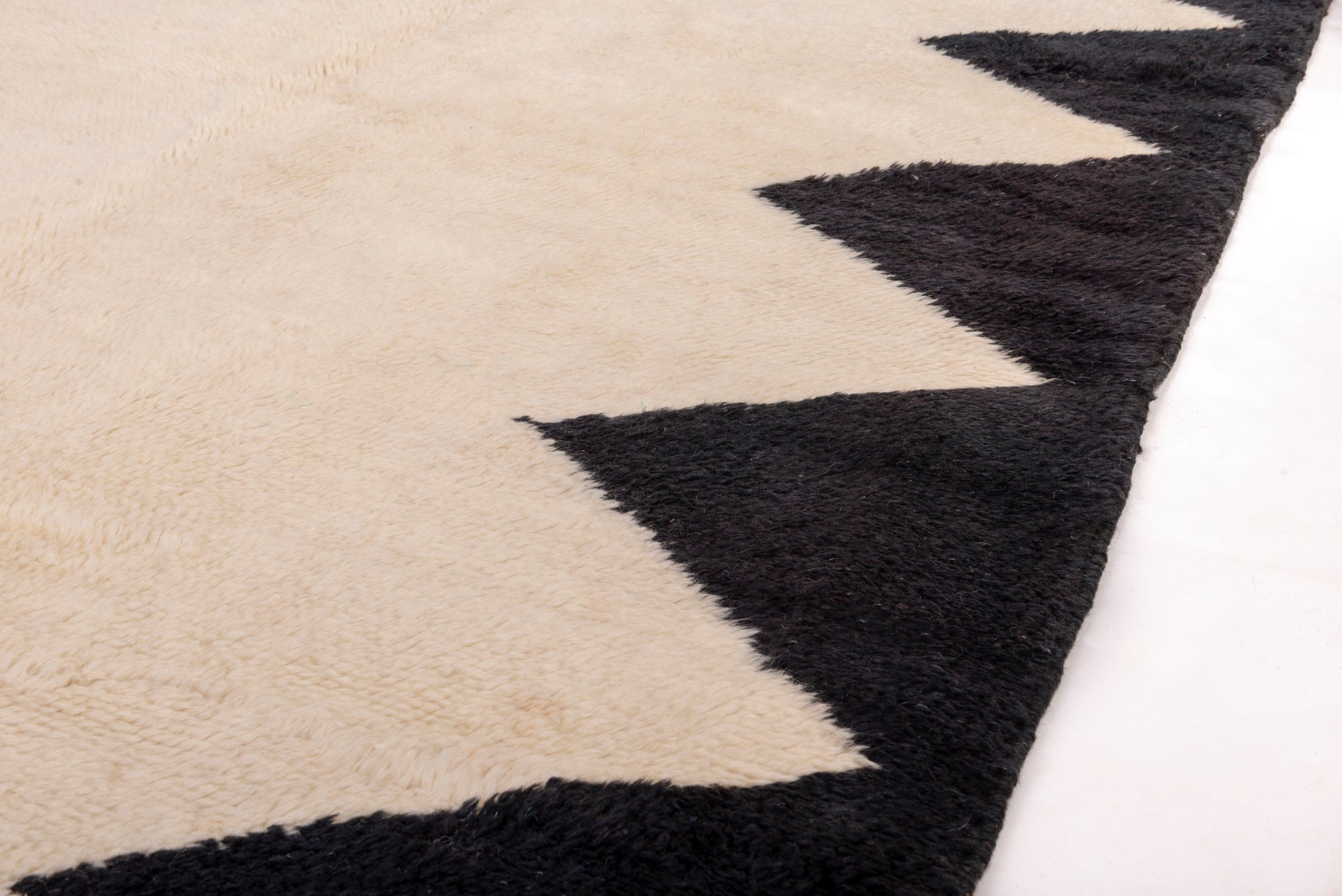Elevate your space with our Ivory Triangle Border Beni Ourain Rug. This classic piece features a timeless ivory base adorned with a striking black triangle border, creating a harmonious blend of traditional Moroccan design and modern elegance. Crafted with care, this rug adds a touch of sophistication to your decor, making it a perfect addition to your home.