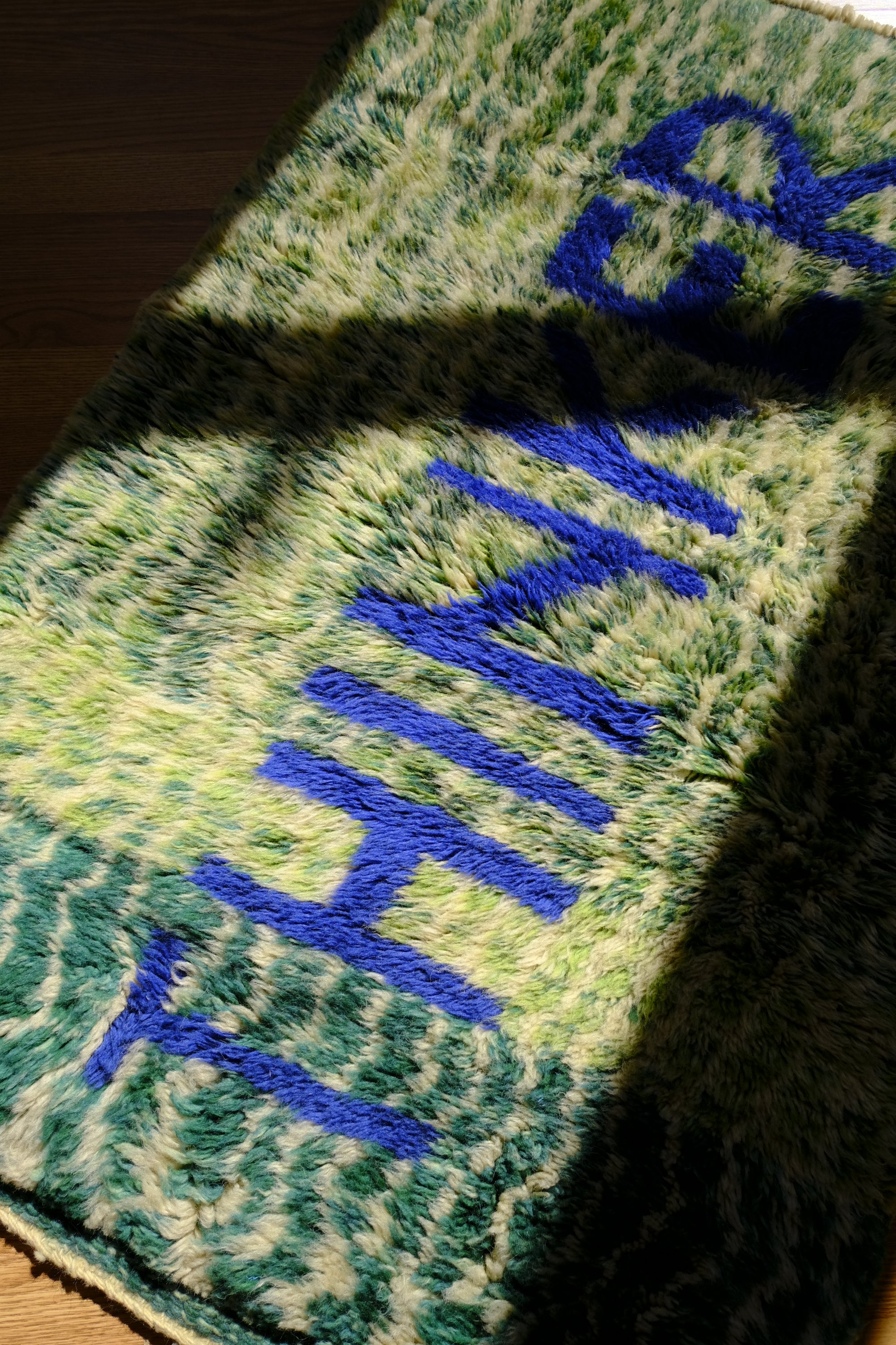 Introducing the 'Verdant Thinker Rug,' where the profound 'Thinker' letter is meticulously woven in blue yarn. Set against a backdrop of unique green and ivory curved wave lines, this rug brings a touch of intellectual charm to your space. Elevate your home with its artistic blend of colors and textures, creating a vibrant and thoughtful ambiance that resonates with modern sophistication.